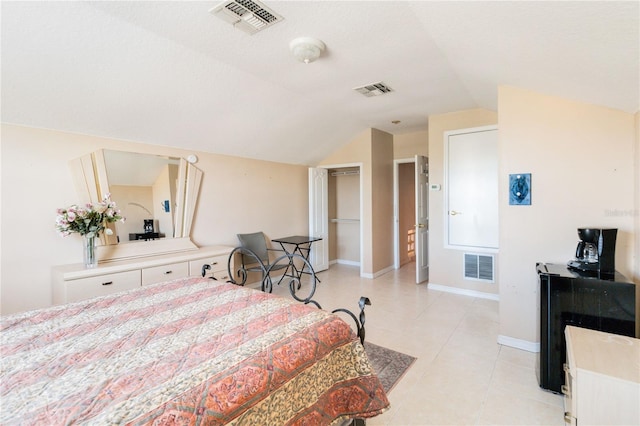 tiled bedroom with a walk in closet, vaulted ceiling, a closet, and a textured ceiling