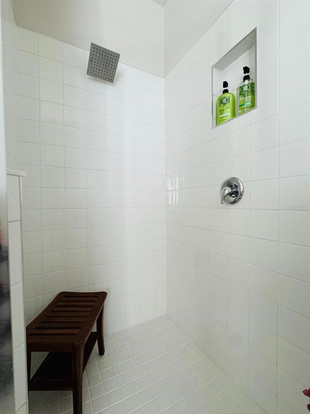 bathroom featuring tile patterned flooring, a tile shower, and tile walls