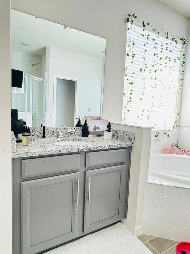 bathroom with tile patterned floors, vanity, independent shower and bath, and a healthy amount of sunlight