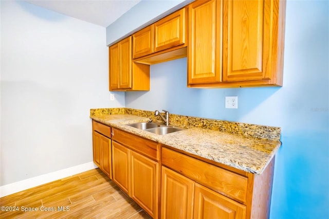 kitchen with light stone countertops, sink, and light wood-type flooring