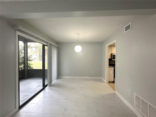 unfurnished dining area featuring marble finish floor, baseboards, visible vents, and a textured ceiling