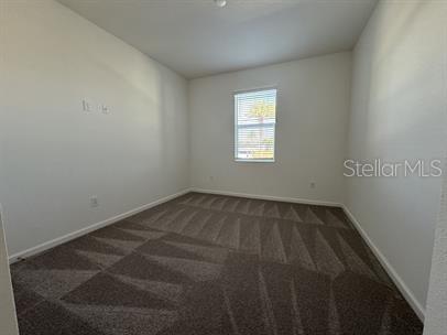 spare room with dark colored carpet