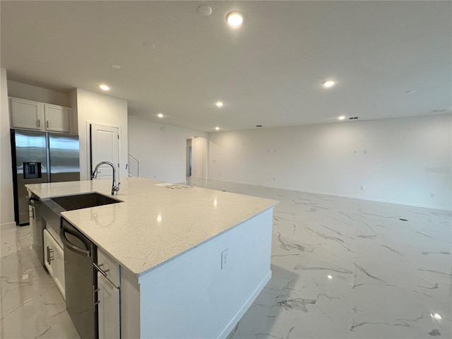 kitchen featuring black dishwasher, sink, white cabinets, light stone countertops, and a center island with sink