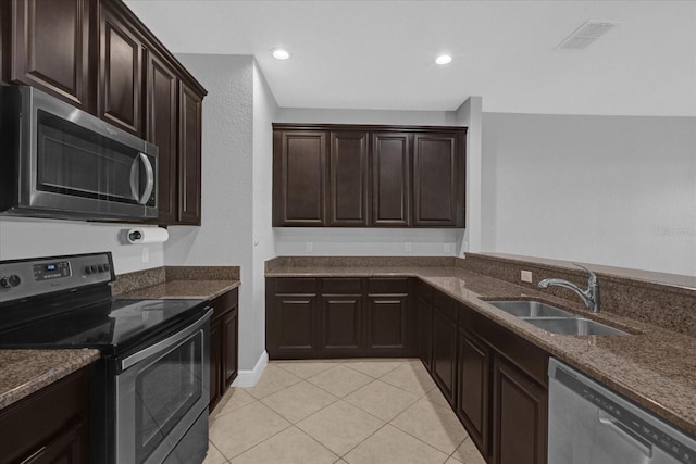 kitchen featuring dark brown cabinets, light tile patterned floors, sink, and appliances with stainless steel finishes