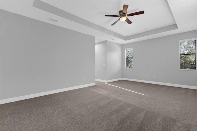 carpeted empty room featuring a tray ceiling and ceiling fan