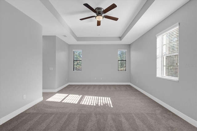 carpeted empty room with a tray ceiling and ceiling fan