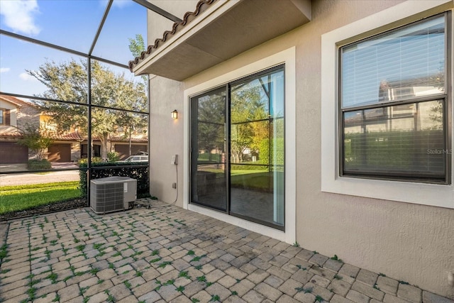 view of patio featuring central air condition unit and glass enclosure