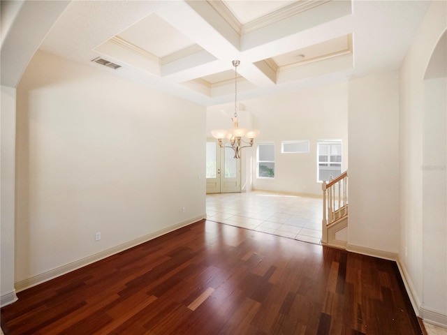 empty room featuring coffered ceiling, ornamental molding, beam ceiling, wood-type flooring, and a chandelier