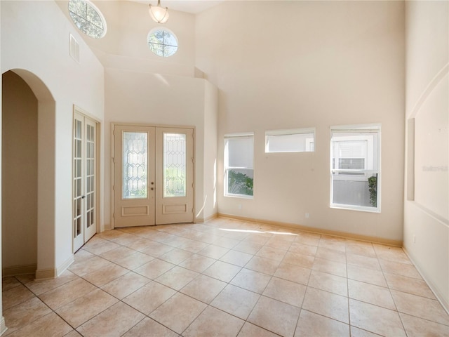 tiled entryway featuring a healthy amount of sunlight, a high ceiling, and french doors