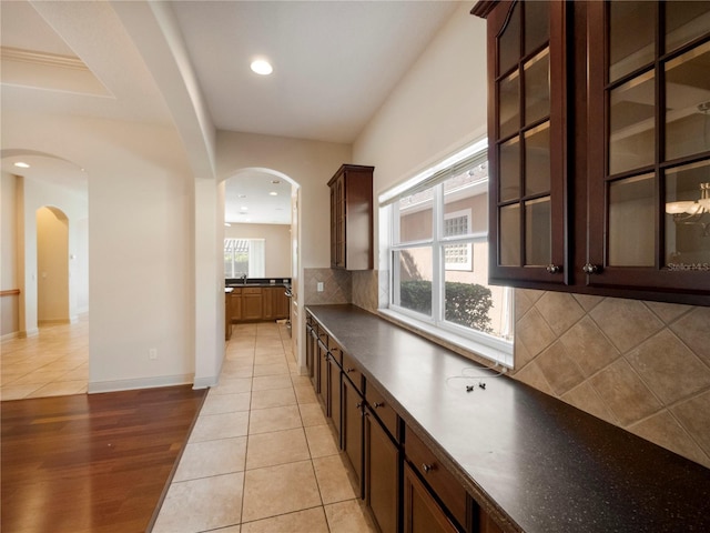 kitchen featuring dark brown cabinetry, light tile patterned floors, and tasteful backsplash