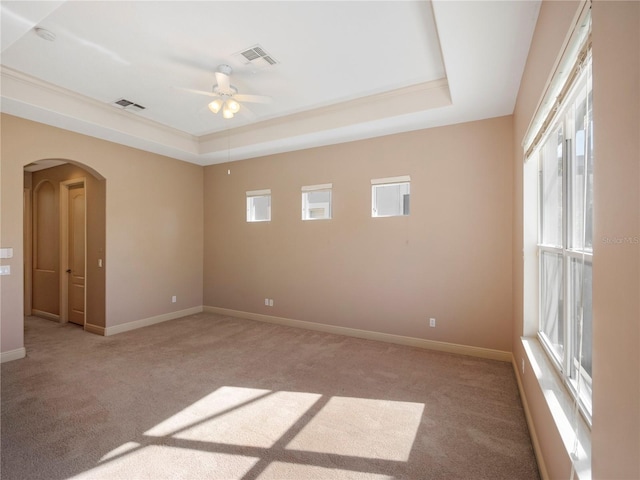 carpeted spare room featuring a raised ceiling and ceiling fan