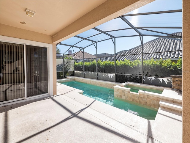 view of pool featuring an in ground hot tub, glass enclosure, and a patio area