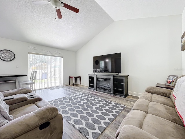 living room with ceiling fan, high vaulted ceiling, light hardwood / wood-style floors, and a textured ceiling