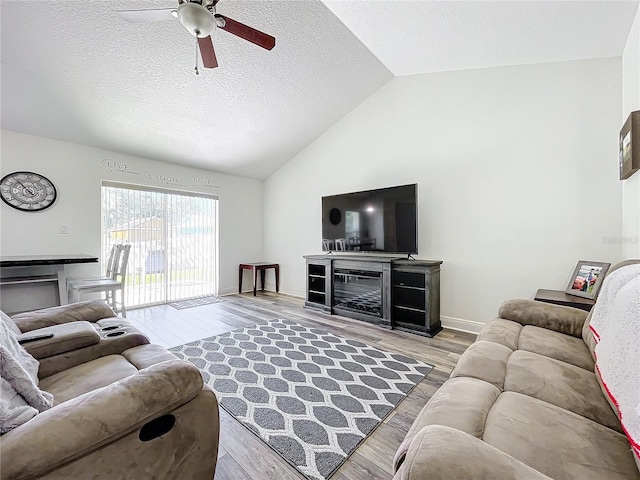 living room featuring a textured ceiling, light hardwood / wood-style flooring, vaulted ceiling, and ceiling fan