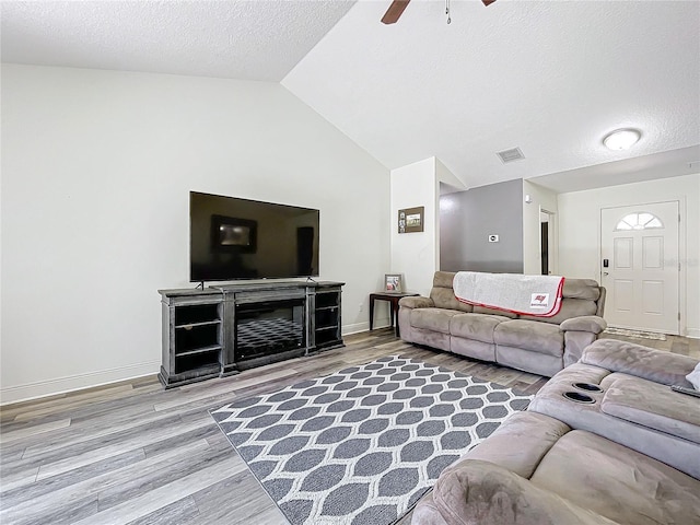 living room featuring a textured ceiling, ceiling fan, wood-type flooring, and vaulted ceiling