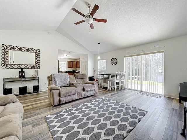 living room with a textured ceiling, ceiling fan, light hardwood / wood-style flooring, and lofted ceiling