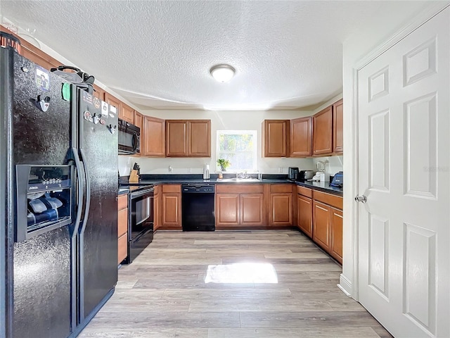 kitchen with sink, black appliances, a textured ceiling, and light wood-type flooring