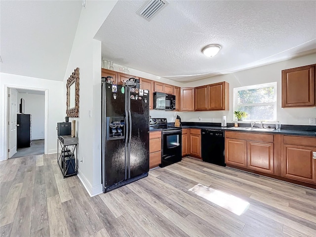 kitchen featuring black appliances, a textured ceiling, and light wood-type flooring