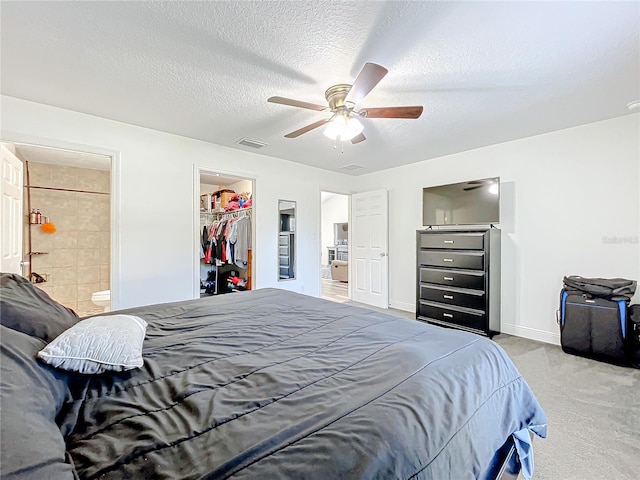 bedroom with light carpet, ensuite bathroom, ceiling fan, a textured ceiling, and a closet