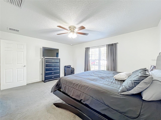 bedroom featuring light carpet, a textured ceiling, and ceiling fan