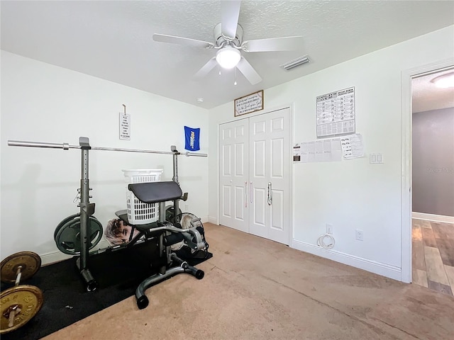 workout area featuring ceiling fan, light hardwood / wood-style flooring, and a textured ceiling