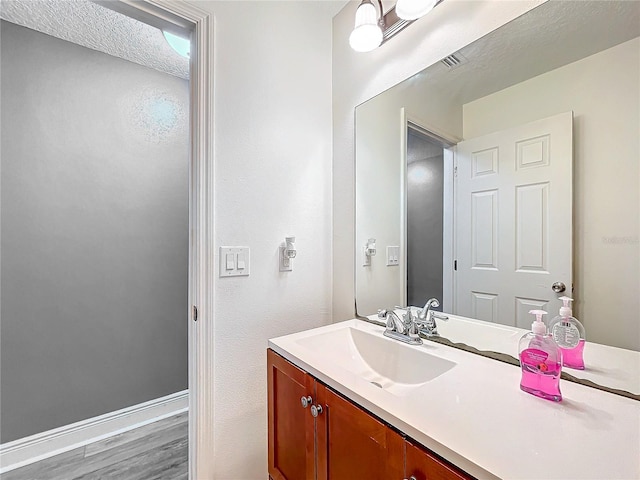 bathroom with wood-type flooring, vanity, and a textured ceiling