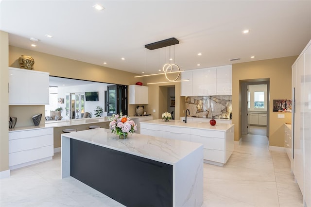 kitchen featuring decorative light fixtures, a healthy amount of sunlight, a spacious island, and white cabinetry