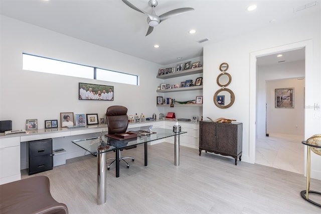 home office featuring ceiling fan, light wood-type flooring, and built in desk