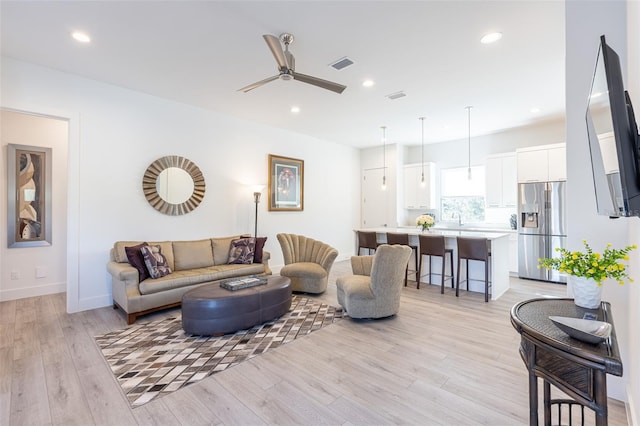 living room featuring ceiling fan, light hardwood / wood-style flooring, and sink