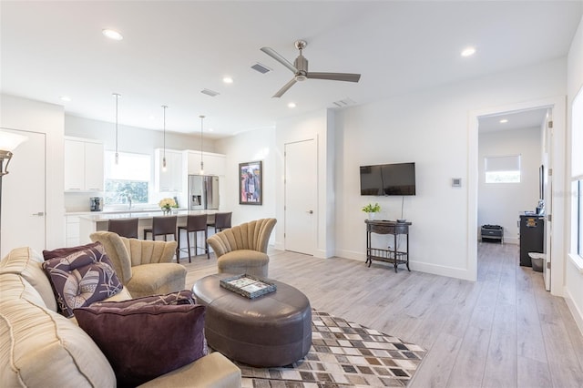 living room with ceiling fan, light wood-type flooring, and sink