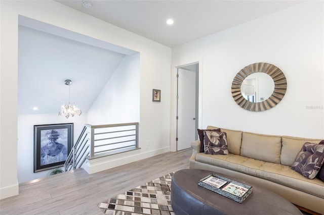 living room with light hardwood / wood-style floors, lofted ceiling, and a notable chandelier