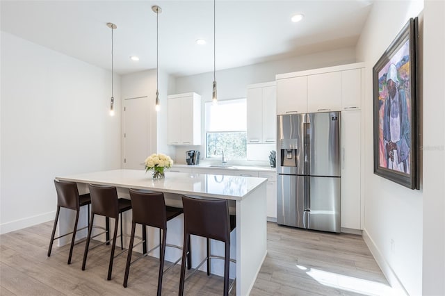 kitchen with a center island, light wood-type flooring, white cabinetry, and stainless steel refrigerator with ice dispenser