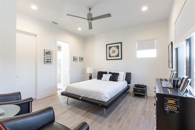 bedroom featuring light hardwood / wood-style floors, ceiling fan, and ensuite bathroom