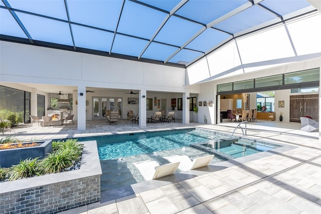 view of pool with glass enclosure, ceiling fan, an in ground hot tub, an outdoor living space with a fire pit, and a patio