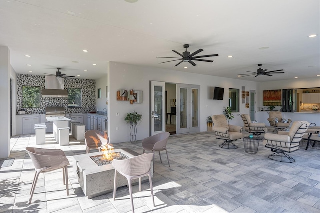 view of patio / terrace with french doors, an outdoor kitchen, and an outdoor fire pit