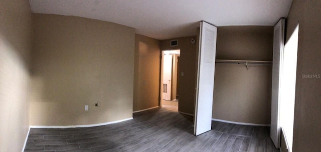 unfurnished bedroom featuring dark hardwood / wood-style floors and a closet