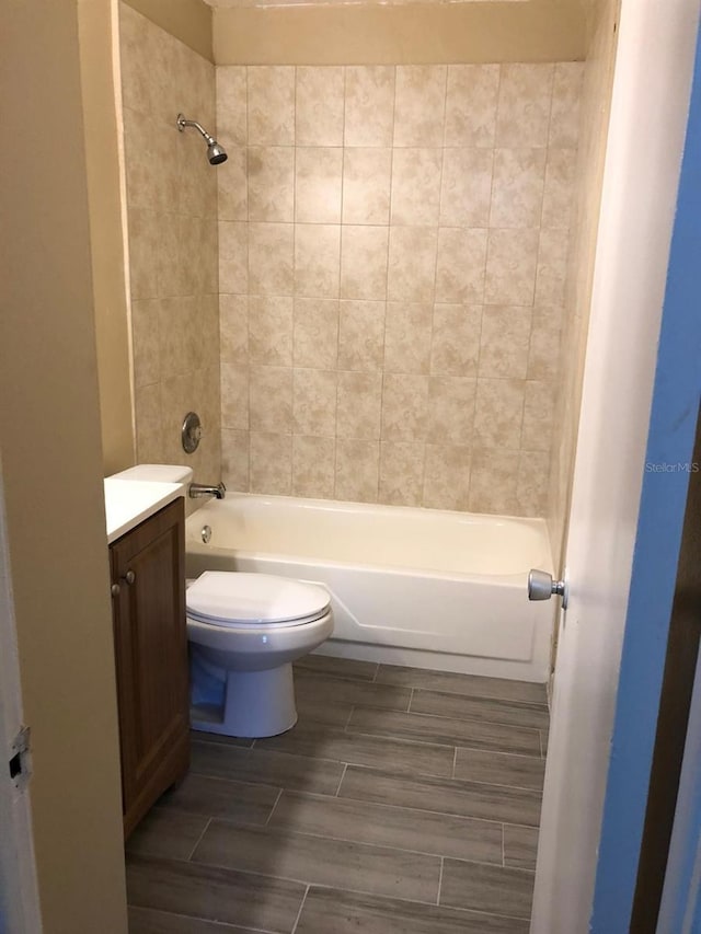 full bathroom featuring tiled shower / bath, vanity, and toilet