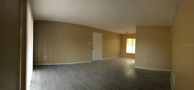 empty room featuring vaulted ceiling and dark hardwood / wood-style floors