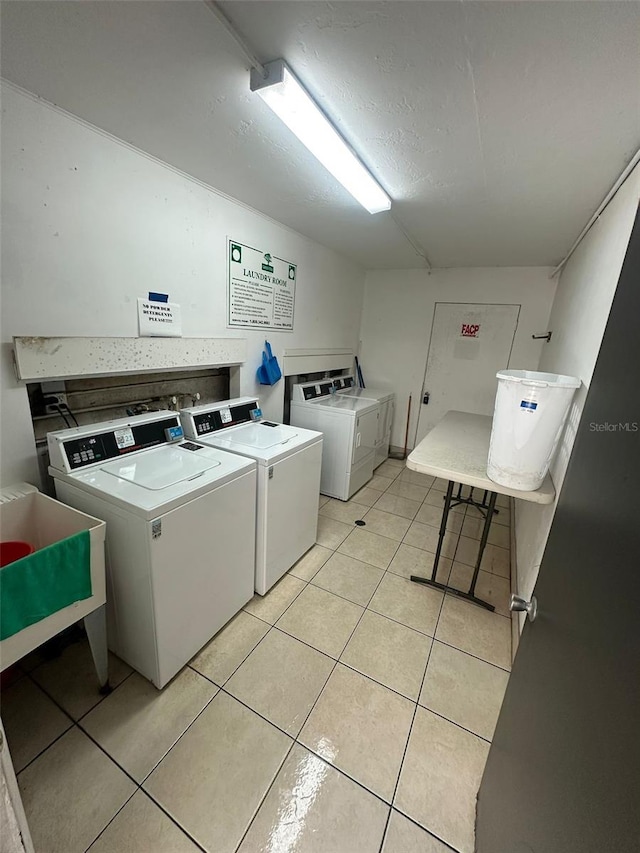 clothes washing area featuring light tile patterned flooring, sink, and washing machine and clothes dryer