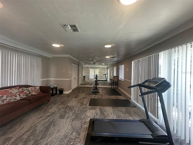 exercise area with dark carpet, a textured ceiling, and ornamental molding