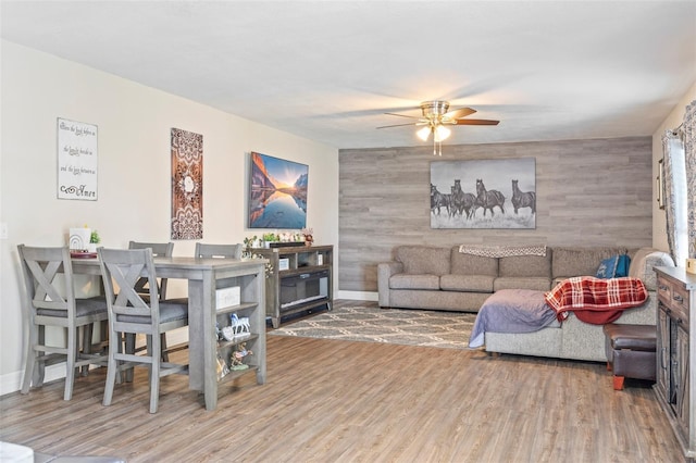 living room with wooden walls, hardwood / wood-style floors, and ceiling fan