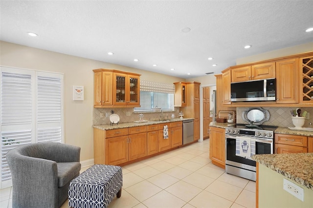 kitchen featuring light stone counters, light tile patterned floors, appliances with stainless steel finishes, and tasteful backsplash