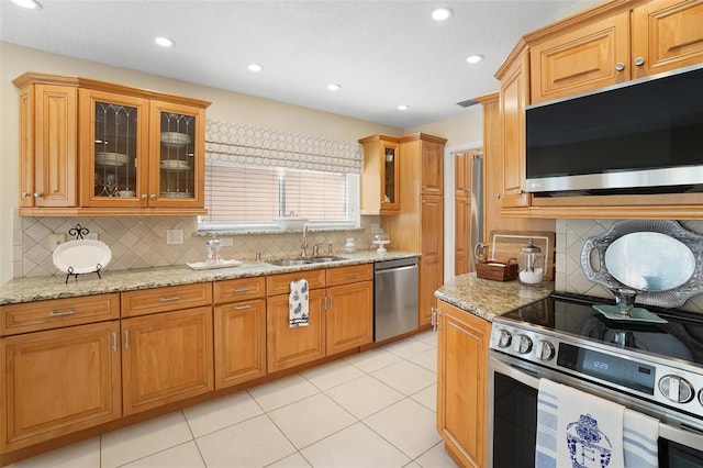 kitchen featuring sink, light tile patterned floors, tasteful backsplash, light stone counters, and stainless steel appliances