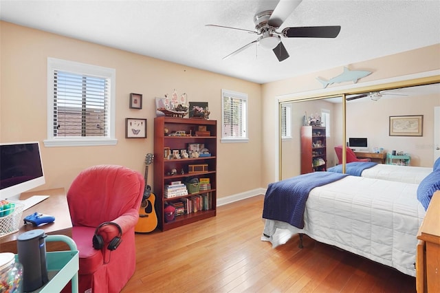 bedroom featuring ceiling fan, a closet, light wood-type flooring, and multiple windows