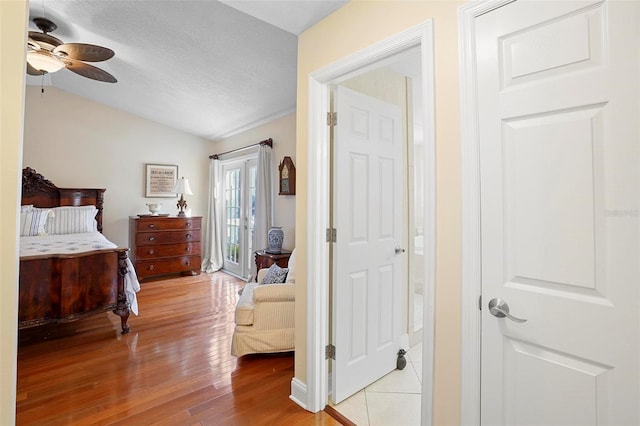 bedroom with ceiling fan, light hardwood / wood-style floors, lofted ceiling, and a textured ceiling