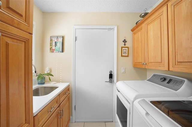 laundry area with cabinets, a textured ceiling, sink, light tile patterned floors, and washing machine and clothes dryer