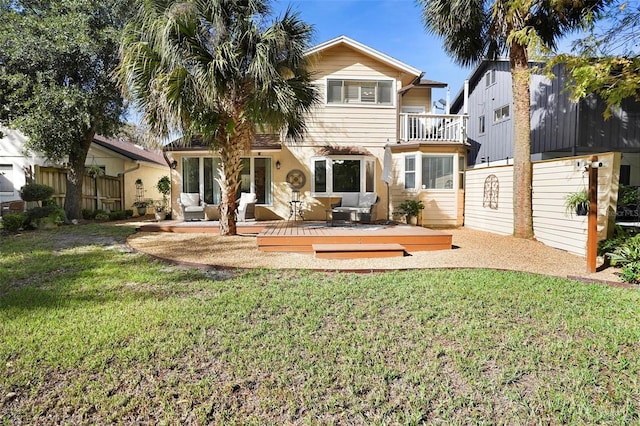 rear view of property featuring a balcony, a yard, and a wooden deck