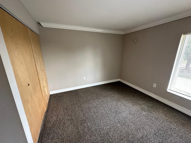 unfurnished bedroom with a closet, ornamental molding, and dark colored carpet