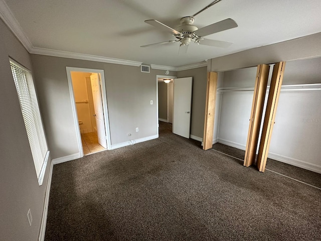 unfurnished bedroom with dark colored carpet, two closets, ceiling fan, and crown molding