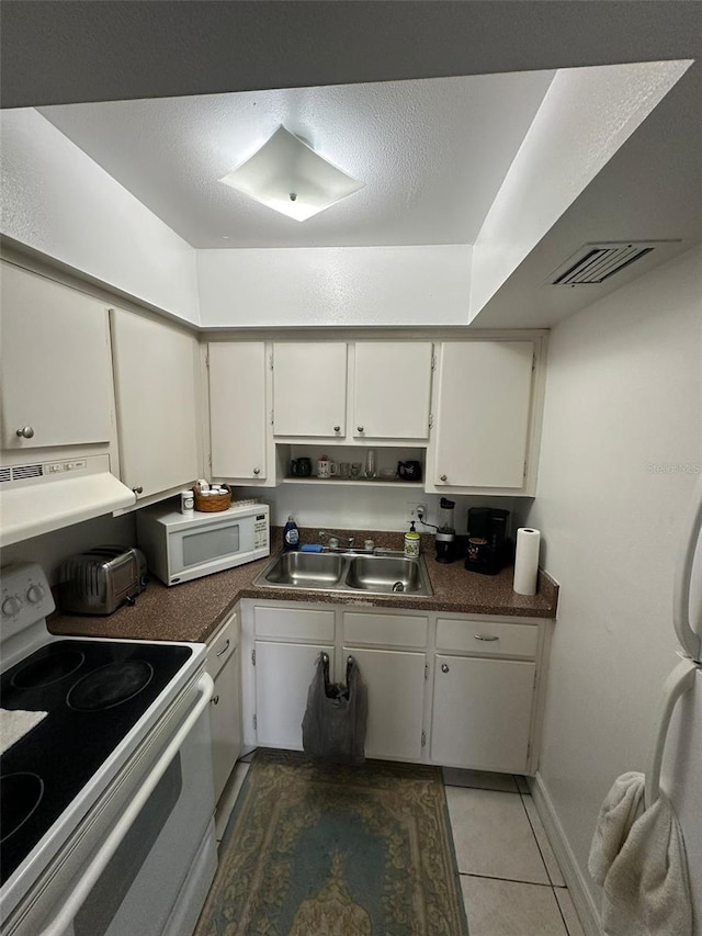 kitchen with white appliances, dark tile patterned flooring, sink, white cabinetry, and extractor fan